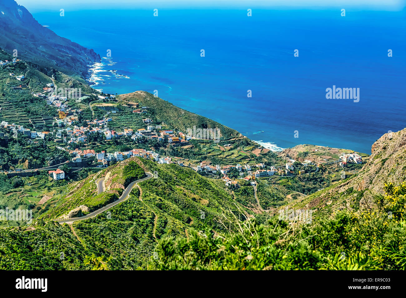 Berge und Wolken mit kleinen Stadt oder Dorf Landschaft in der Nähe der Küste oder Ufer von Atlantik auf Teneriffa Kanarische Insel Stockfoto
