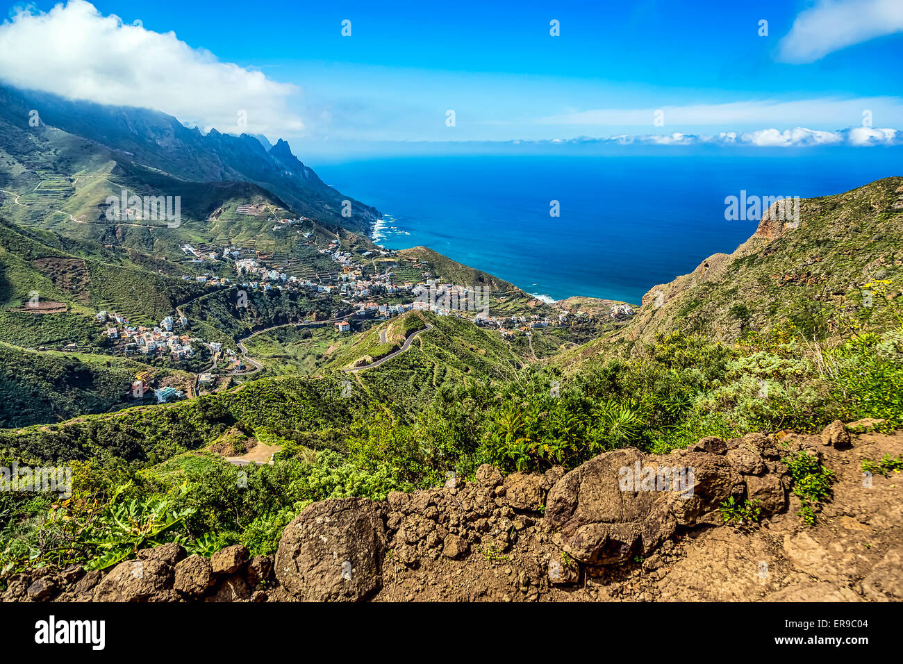 Berge und Wolken mit kleinen Stadt oder Dorf und Himmel Horizont Landschaft in der Nähe der Küste des Ozeans in Teneriffa Kanarische Insel Stockfoto