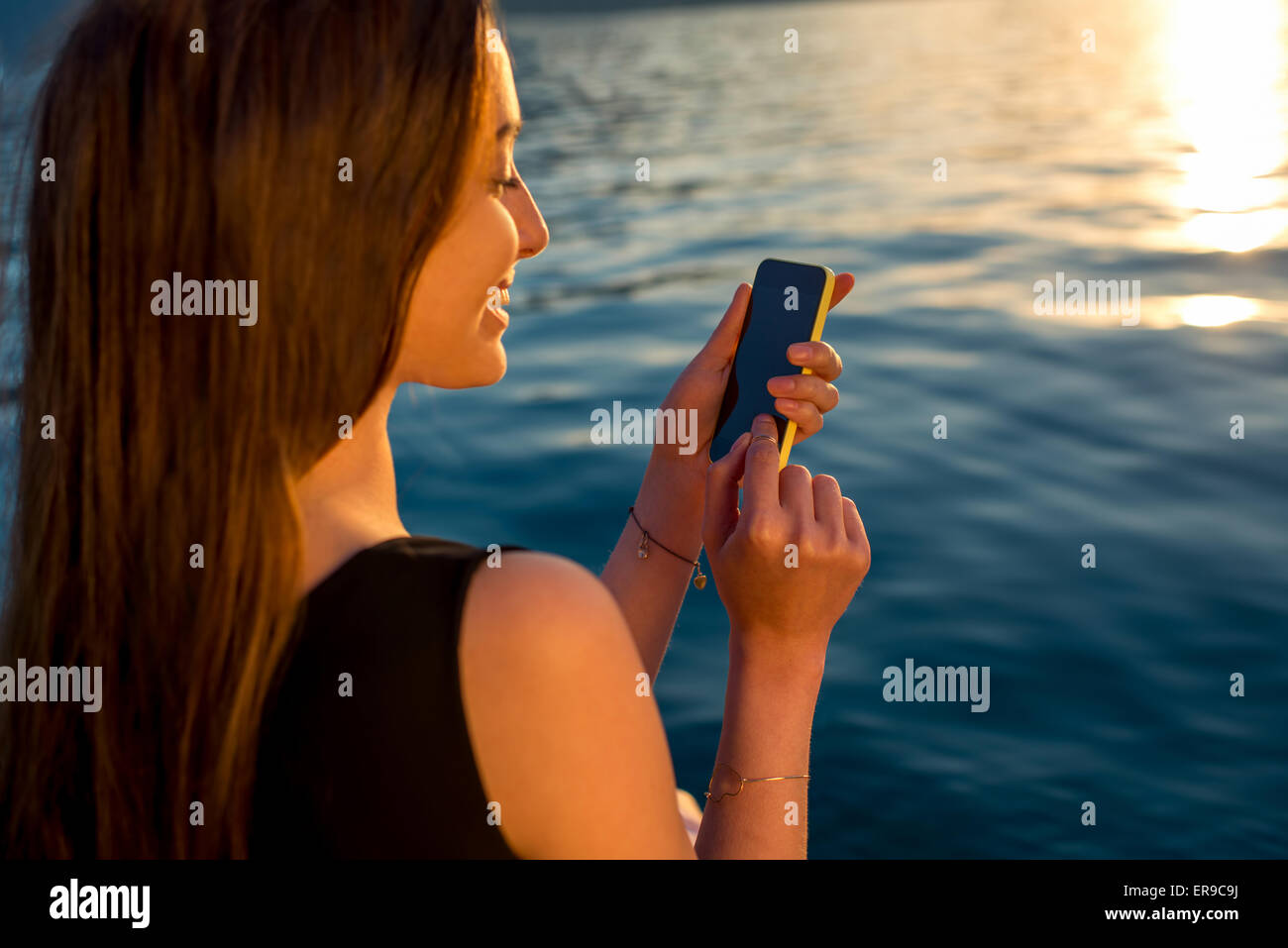Junge Frau mit Telefon bei Sonnenaufgang Stockfoto