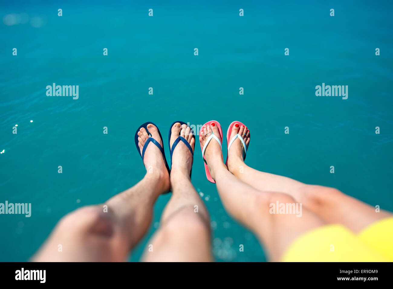 Paares Beine in Pantoffeln auf dem Meer Hintergrund Stockfoto