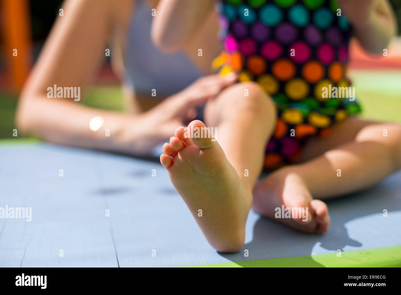 Mutter, hält ihre kleine Tochter Füße tragen bunte Badeanzüge auf der Tabelle Nahaufnahme Stockfoto