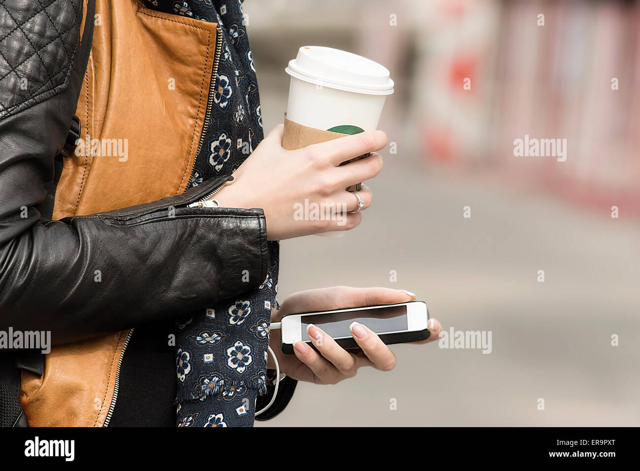 Ausgestattet mit Kaffee und Handy in der Stadtstraße. Konzept des modernen Stadtlebens. Stockfoto