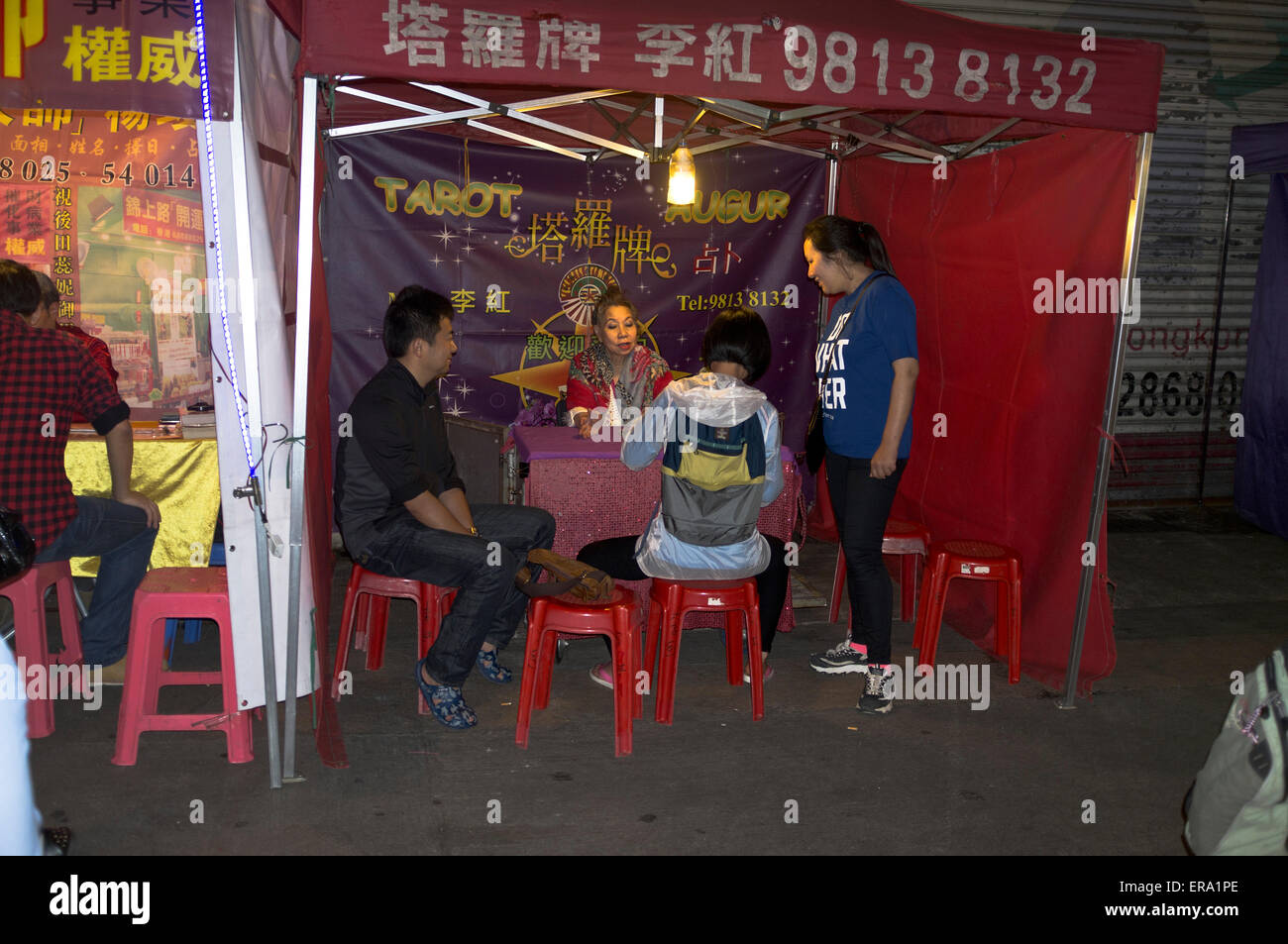 Dh Temple Street Market Yau MA Tei HONG KONG Familie mit wahrsagerin Stall chinesische Frau erzählen Stockfoto