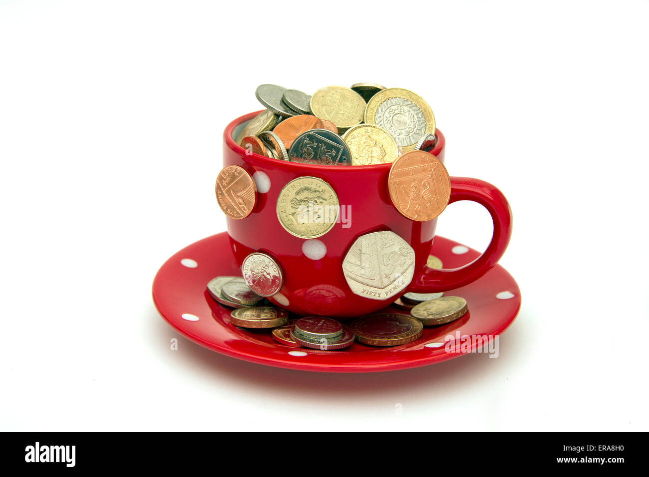"My Cup runneth over'a weiße Tasse und Untertasse voll von GBP britische Münzen verschütten out.a UK Geld Finanzen Wirtschaft Münzen Reichtum Stockfoto