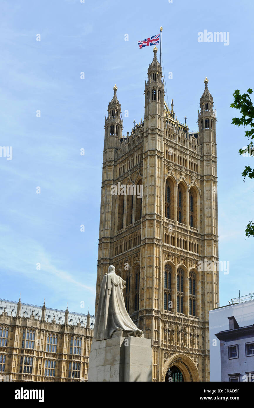 Statue von König George V und Victoria Tower mit der Union Jack-Flagge am Palace of Westminster, London, England. Stockfoto