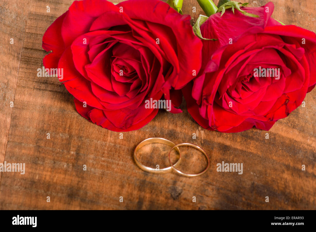 Gold Bands auf Holztisch mit roten Rosen Stockfoto