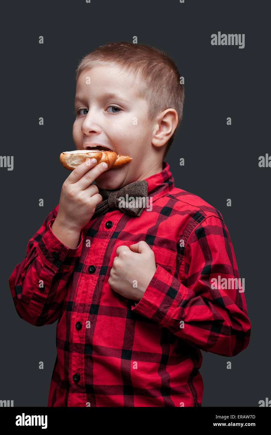 Kleiner Junge Essen einen Laib Brot isolierten auf dunklen Hintergrund Stockfoto