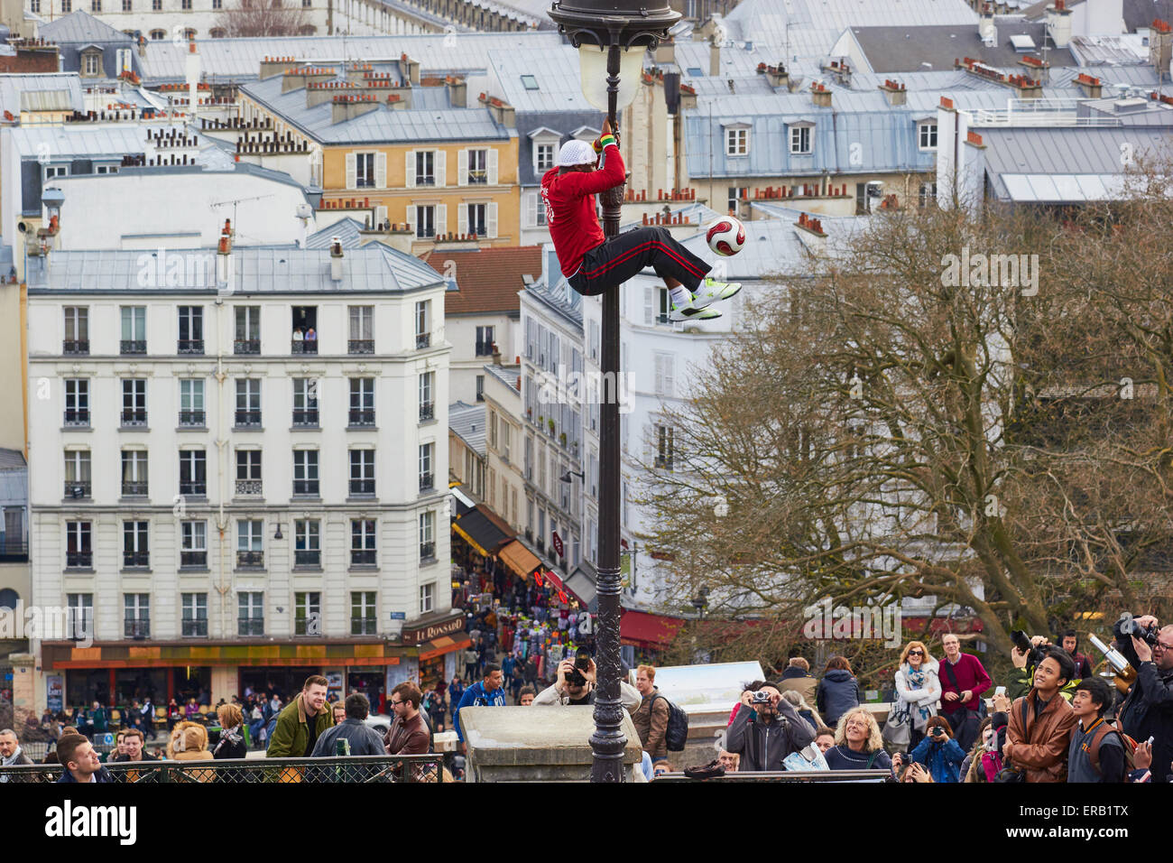 Ausgleich eines Spinnerei Fußballs beim Klettern auf einer Straßenlaterne Straßenkünstler beobachtet von Touristen Montmartre Paris Frankreich Stockfoto