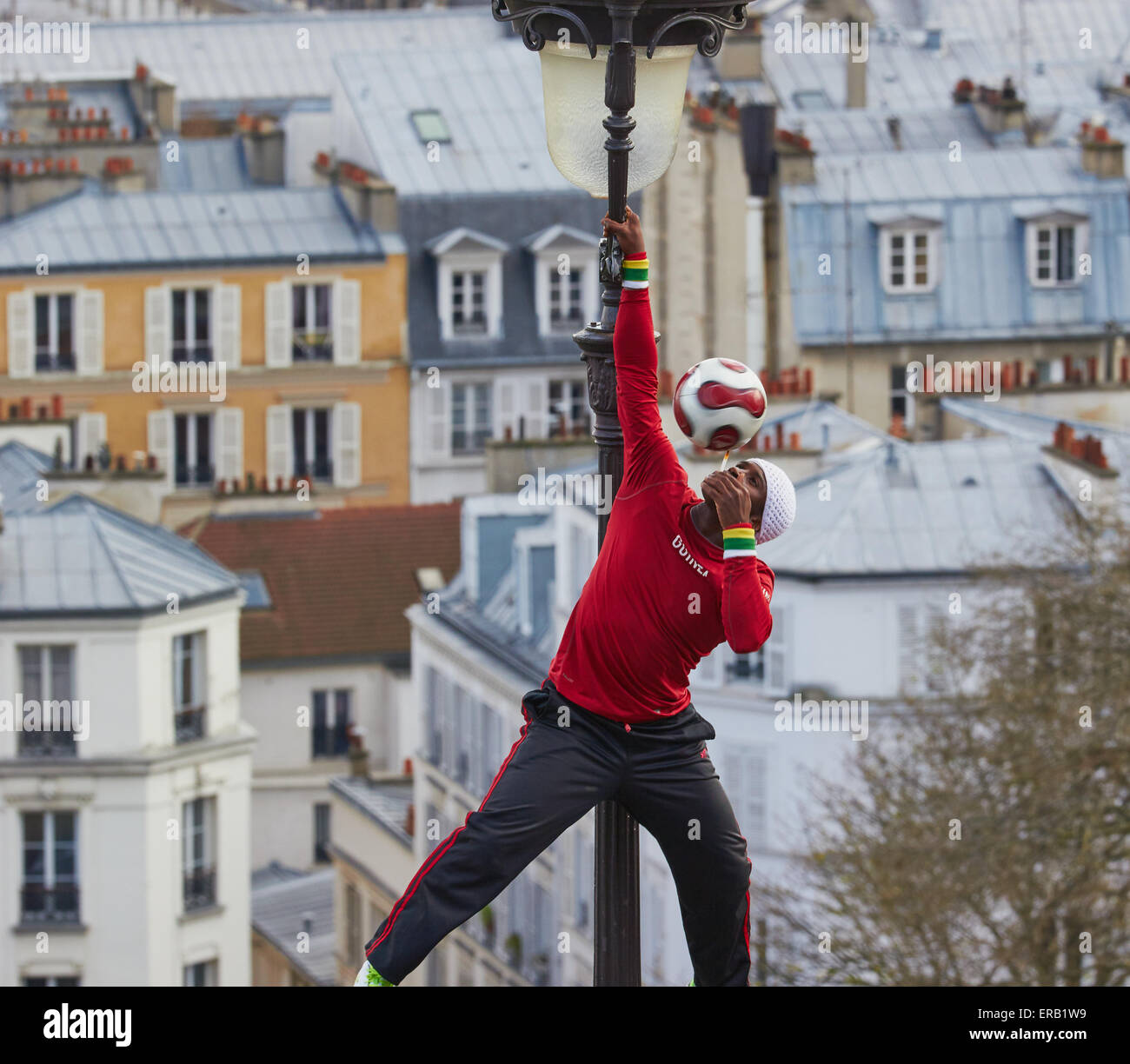 Straßenkünstler Ausgleich einen Spinnen-Fußball beim Klettern auf einer Straßenlaterne Paris Frankreich Europa Stockfoto