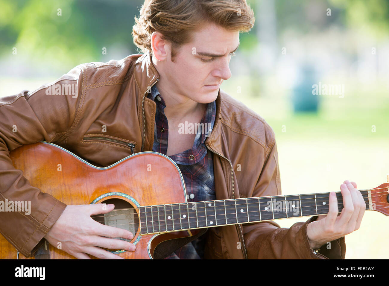 junger Mann spielt Gitarre in einem park Stockfoto