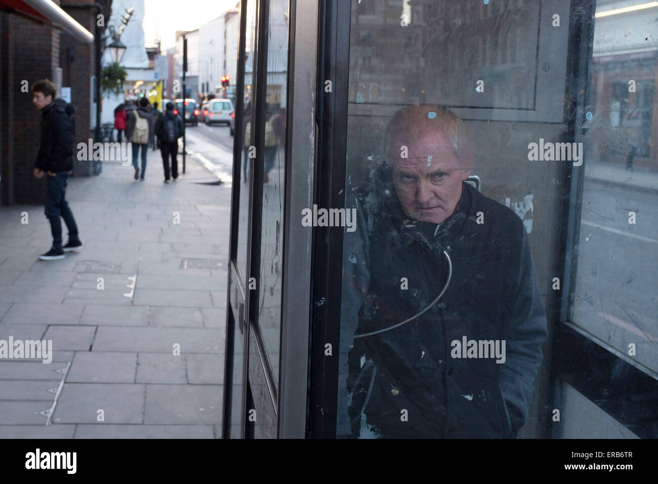 Man spricht in einer öffentlichen Telefonzelle im Bezirk, London, UK. Stockfoto