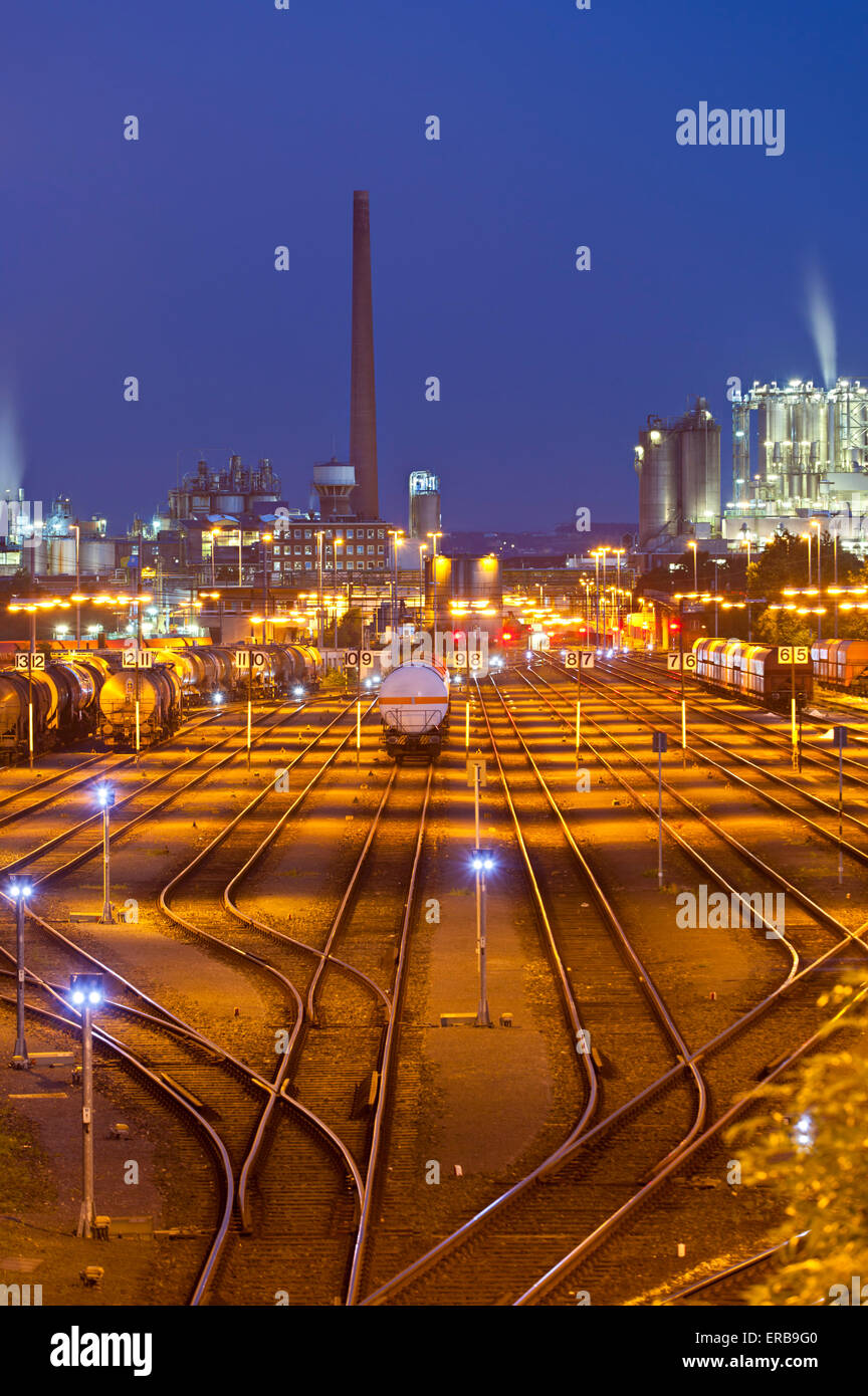 Eine beleuchtete Rangierbahnhof mit Zügen und andere Industrie im Hintergrund in der Nacht Stockfoto