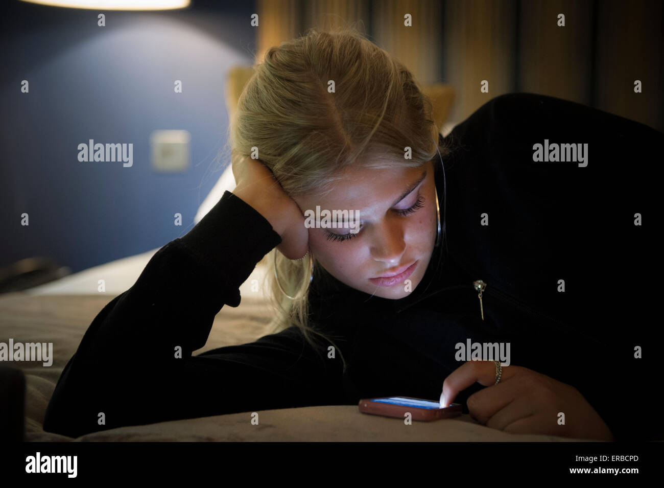 Ein blonder Teenager spielt mit ihrem iphone Stockfoto