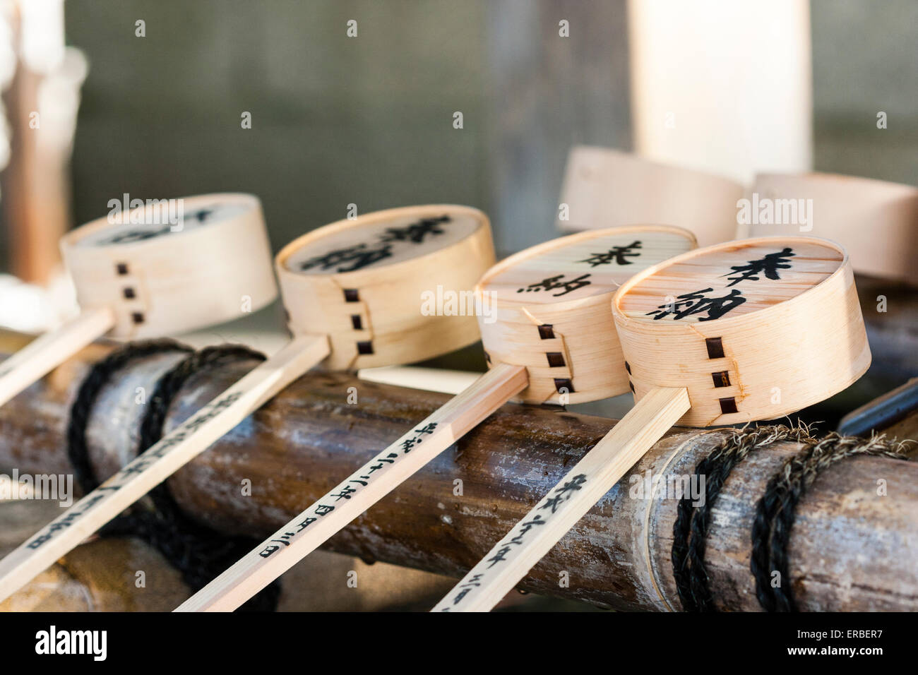 Japan, Kyoto, Yasaka-Schrein. Reinigungsbrunnen, Temizuya, mit Nahaufnahme der Reihe von vier Kanji eingeskripted Schöpfkellen, oder Dippers, ruhend auf Bambusrohr. Stockfoto