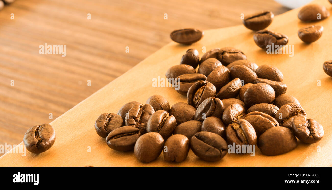 Kaffeebohnen in Form von Herzen auf Holzbrett angeordnet Stockfoto