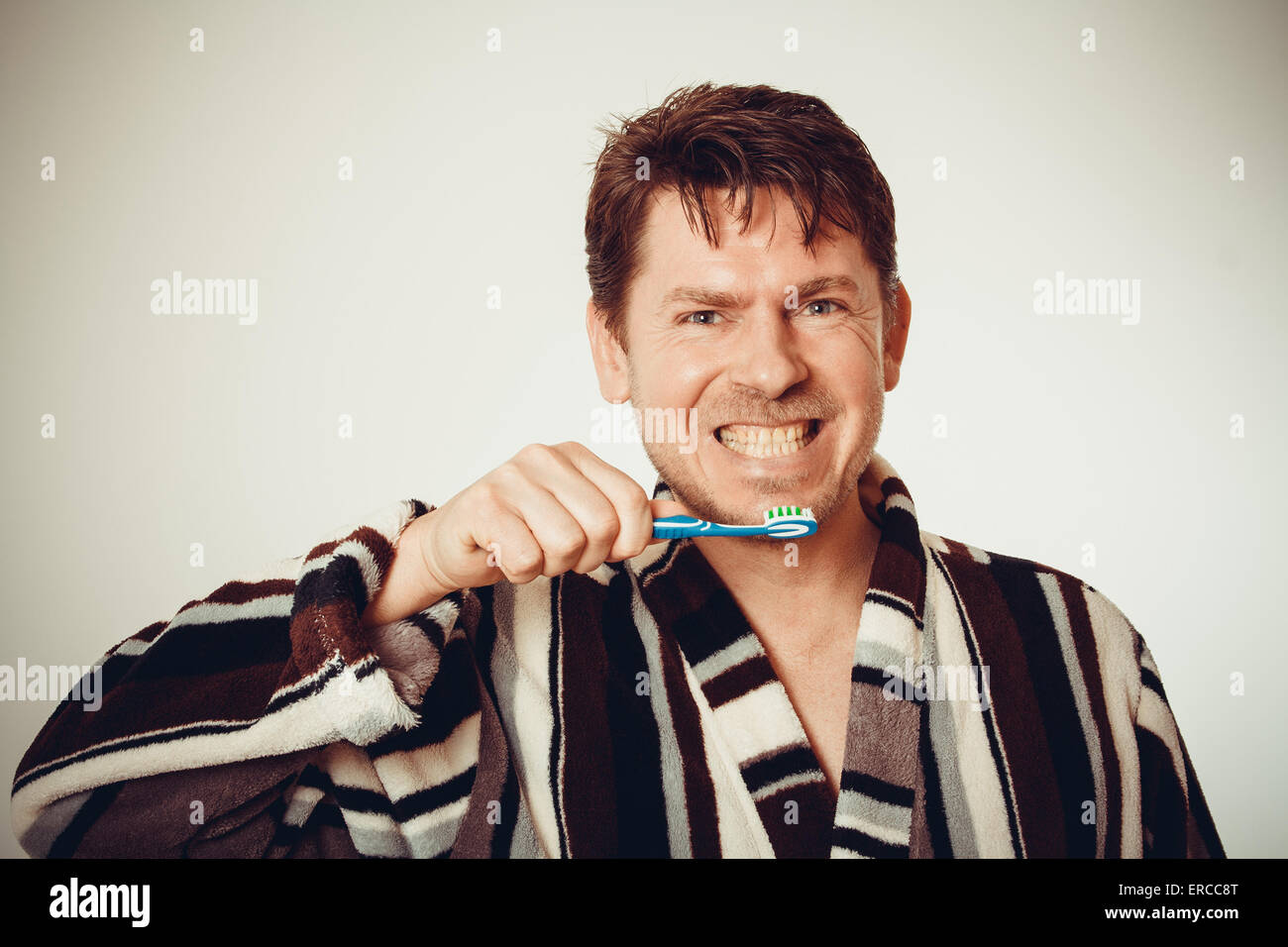 Gut gelaunte Mann im Bademantel Zähneputzen im Vintage look Stockfoto