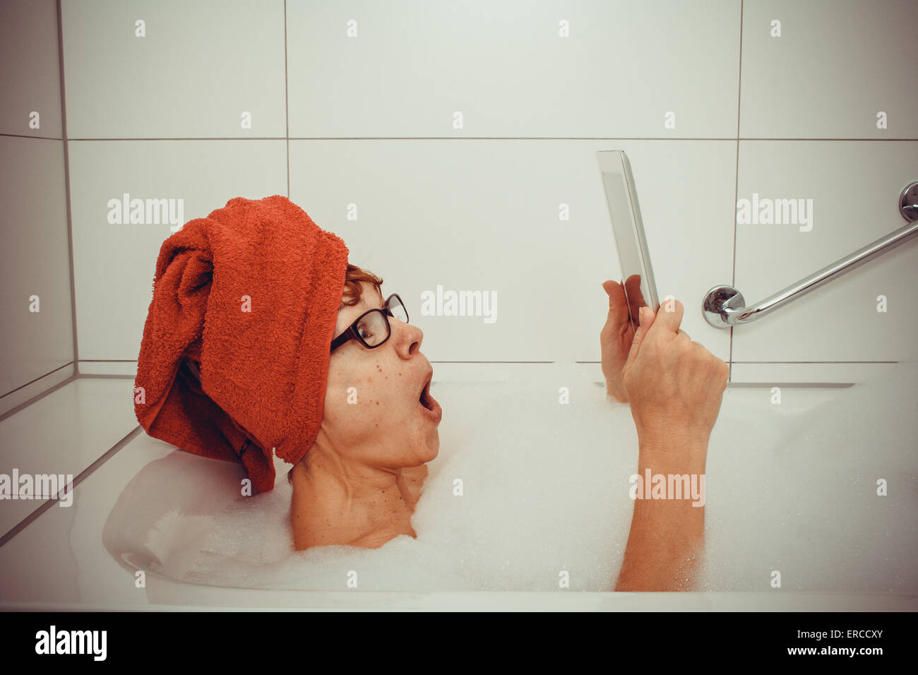 Erregte Frau in der Badewanne mit Tablet-PCs, Nahaufnahme Stockfoto