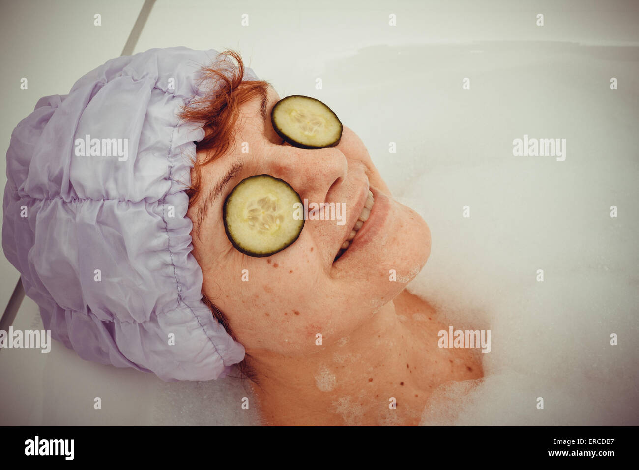Reife Frau in der Badewanne mit Gurkenscheiben auf Spektakel, Retro-Stil Stockfoto