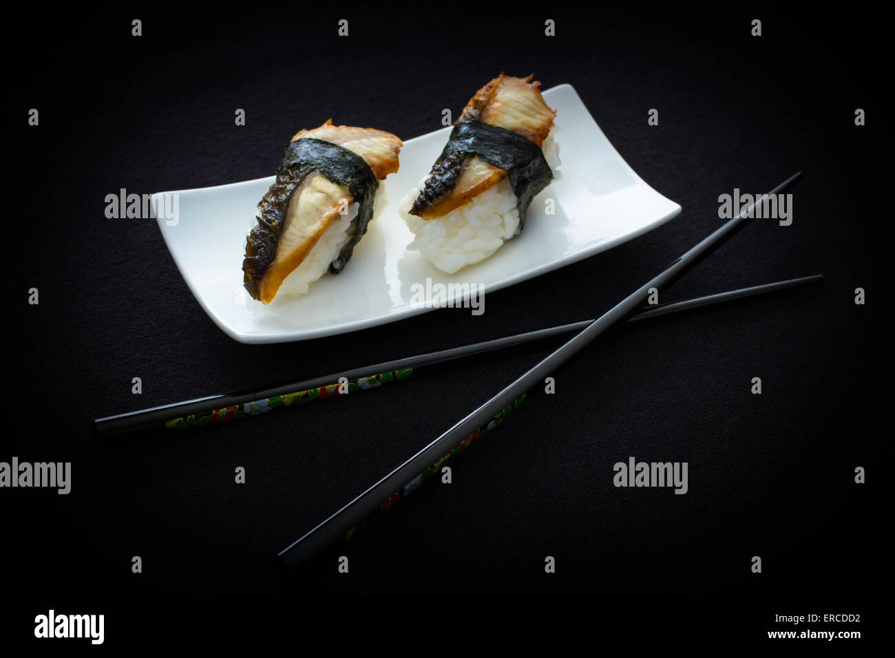 Zwei Nigiri Aal Sushi mit Stäbchen auf schwarz, Top Sicht Stockfoto