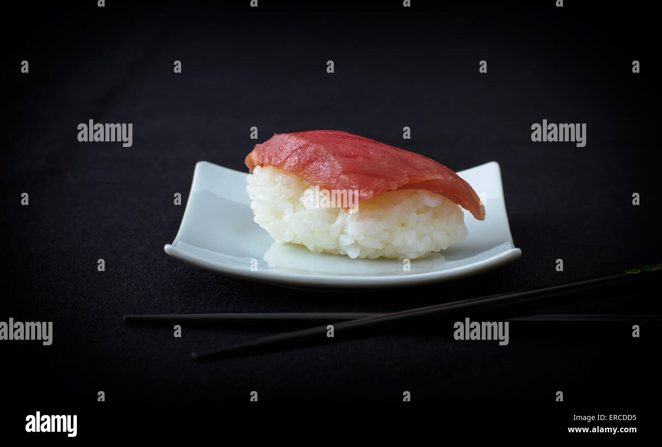 Nigiri-Thunfisch-Sushi mit Stäbchen auf schwarz, Top Sicht Stockfoto