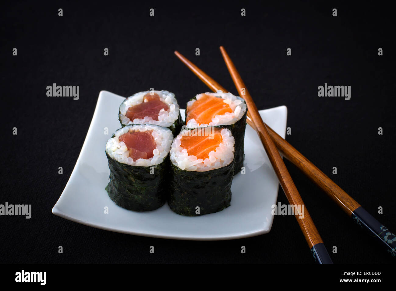 4 Lachs, Thunfisch Maki Sushi und Ess-Stäbchen auf schwarz, Nahaufnahme Stockfoto