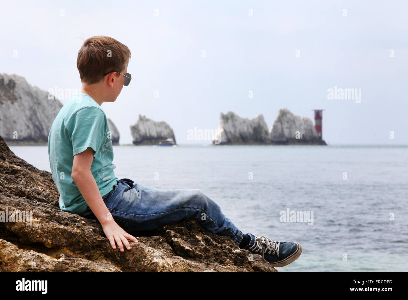 Ein Junge auf einem Felsen, genießen den Blick auf die Nadeln auf der Isle Of Wight (Punkt des Fokus auf den jungen) Stockfoto