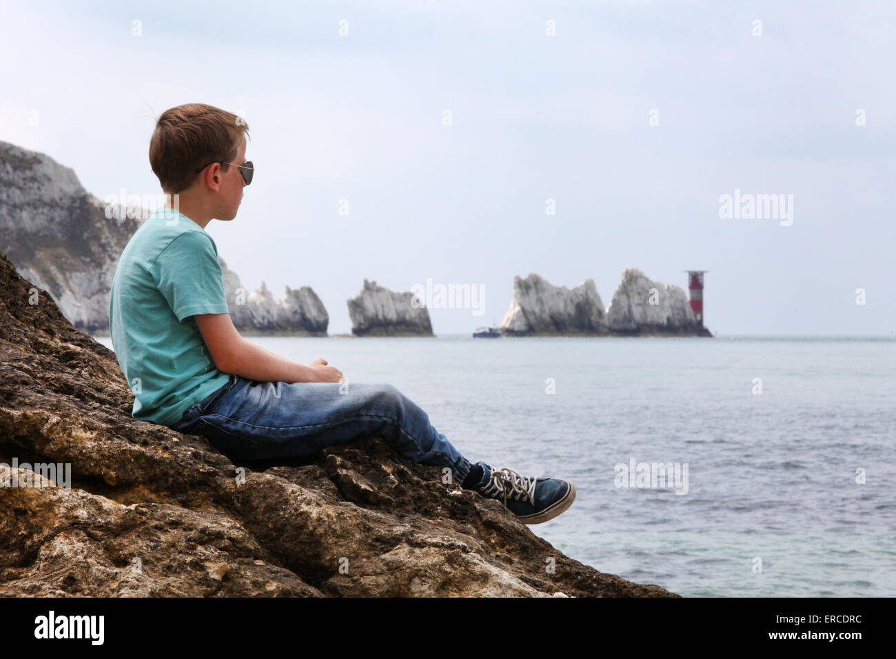 Ein Junge auf einem Felsen, genießen den Blick auf die Nadeln auf der Isle Of Wight (Punkt des Fokus auf den jungen) Stockfoto