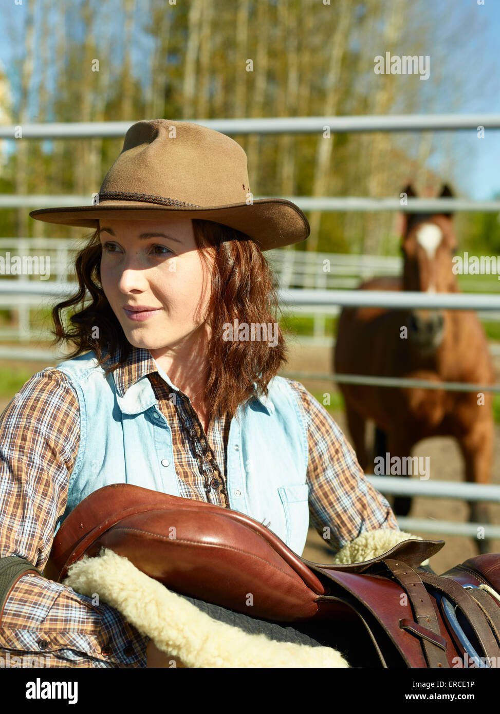 Cowgirl trägt einen Sattel, Pferd auf eine Koppel Stockfoto