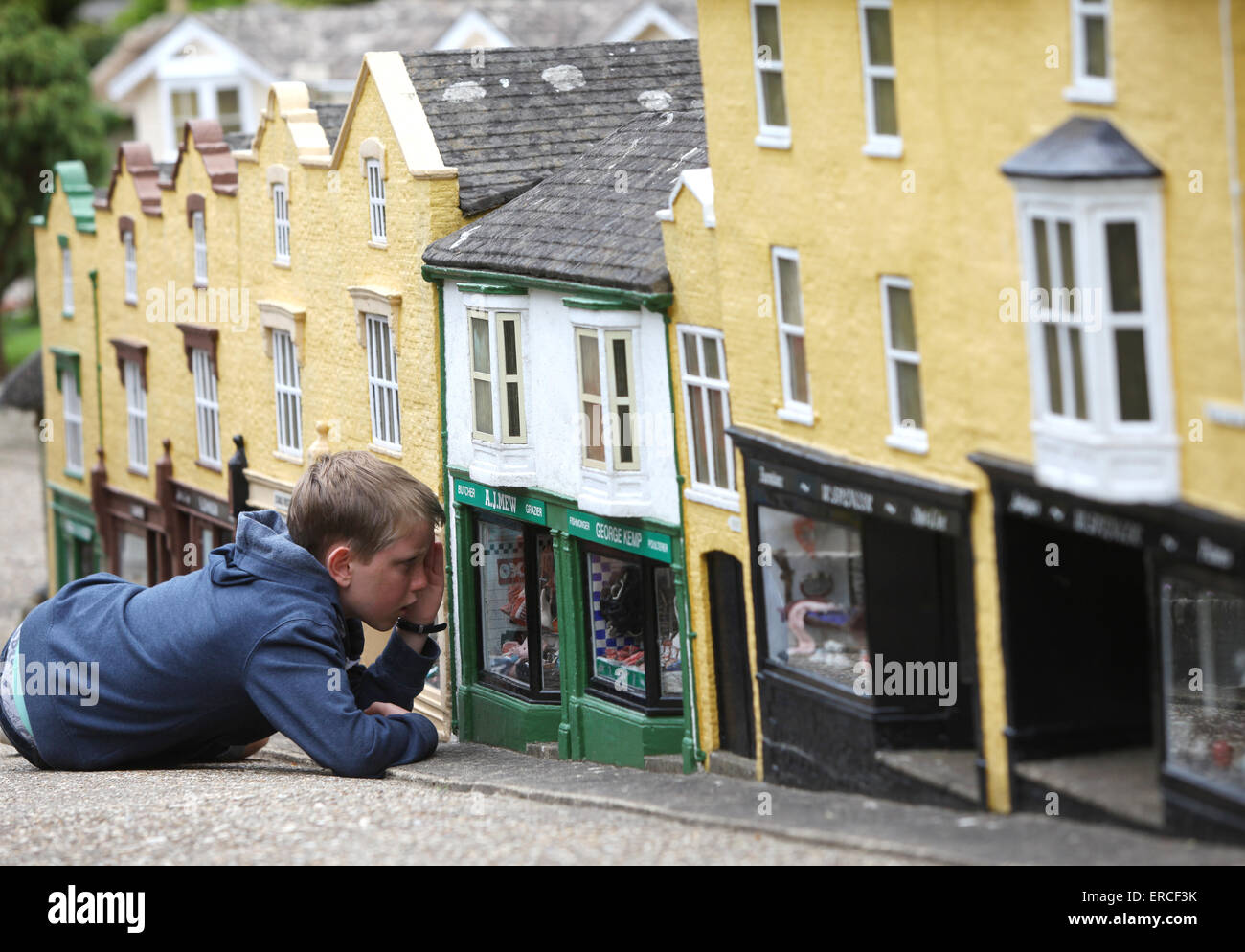Ein Junge sieht aus wie ein Riese, wie er bei einem Besuch in The Model Village in Godshill auf der Isle Of Wight durch ein Schaufenster aussieht Stockfoto