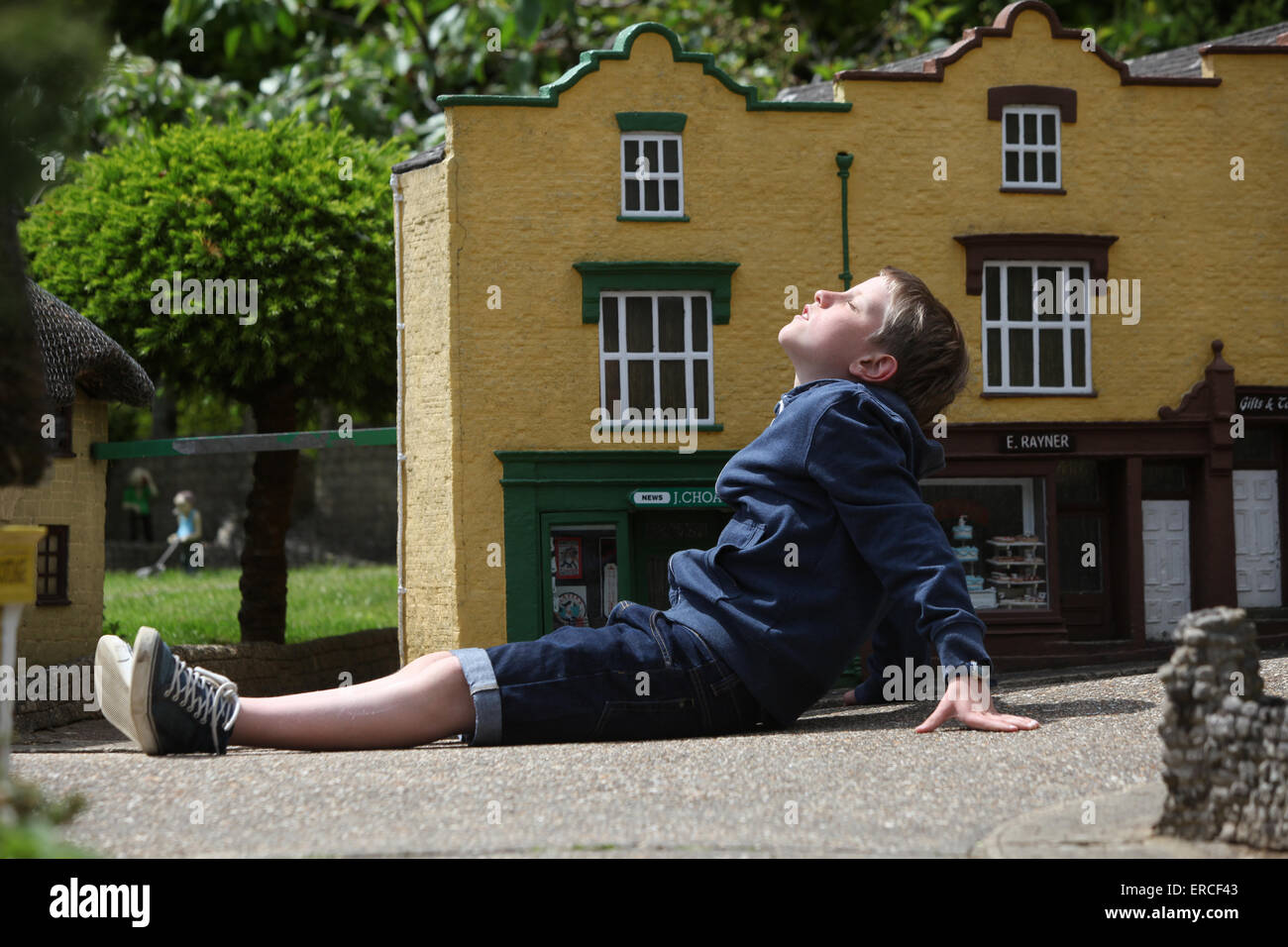 Ein Junge zum Entspannen in der Sonne während eines Besuchs in The Model Village in Godshill auf der Isle Of Wight Stockfoto