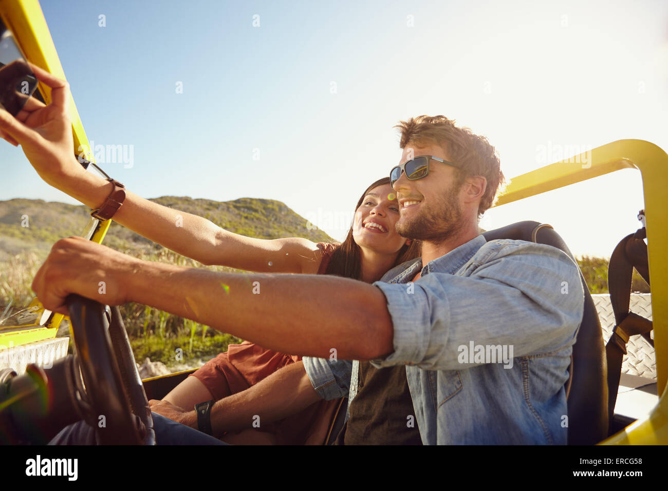 Paar auf Road-Trip, Mann fahren ein Auto und eine Frau nehmen Selfie auf ihr Handy. Stockfoto