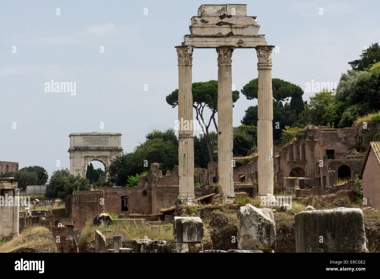 Drei Spalten bleiben aus dem Tempel des Castor und Pollux auf dem Forum Romanum in Rom. Bogen von Titus im Hintergrund. Stockfoto
