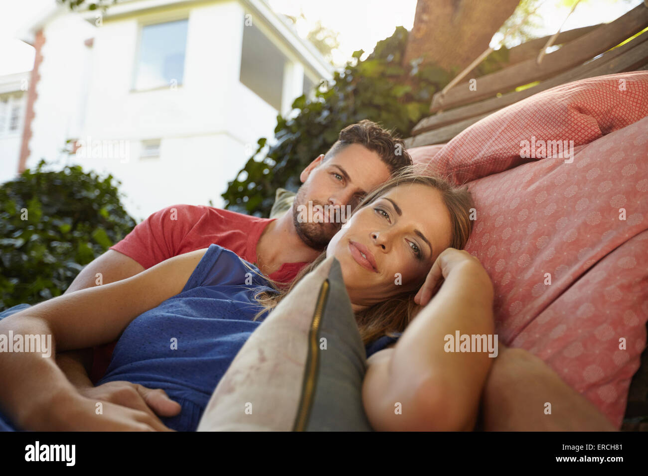 Romantische junge caucasian Paar gemeinsam auf einer Hängematte entspannen und Blick in die Kamera. Junger Mann und Frau im Garten Hängematte in t Stockfoto
