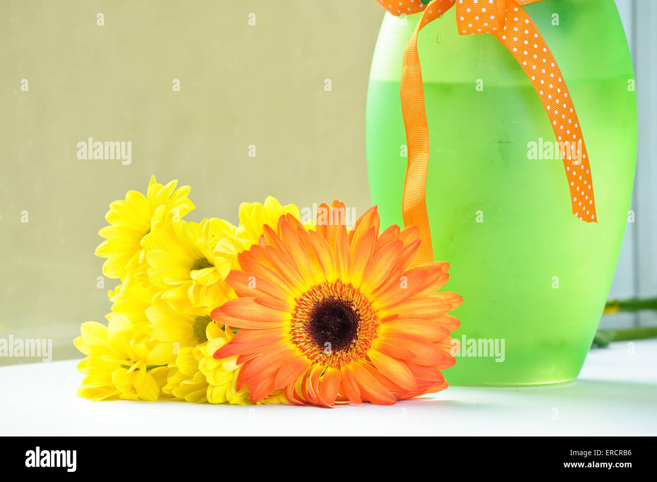 Die orange Gerbera und gelbe Daisy in der Nähe ein grünes Glasvase Stockfoto