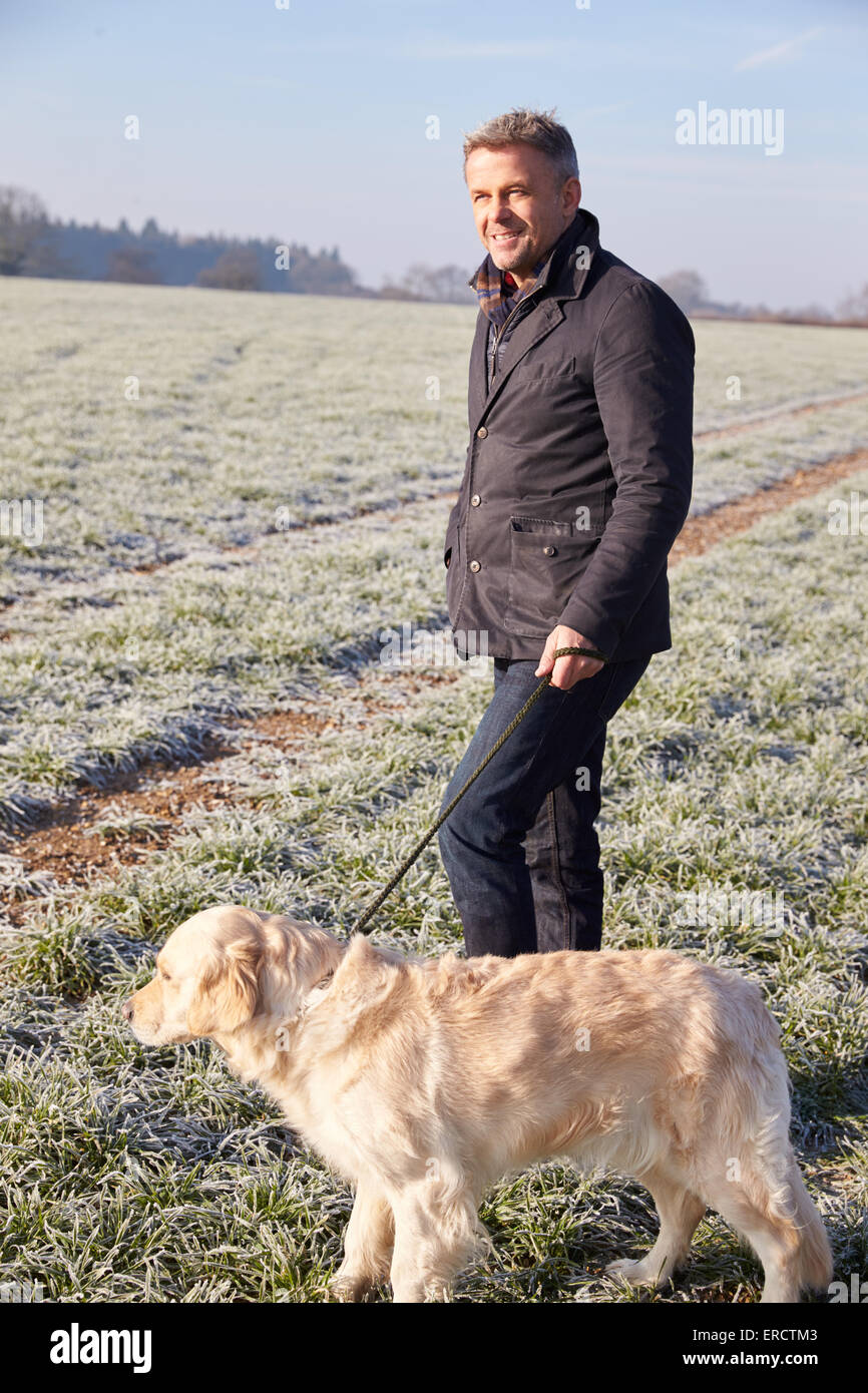 Reifer Mann zu Fuß Hund In frostigen Landschaft Stockfoto