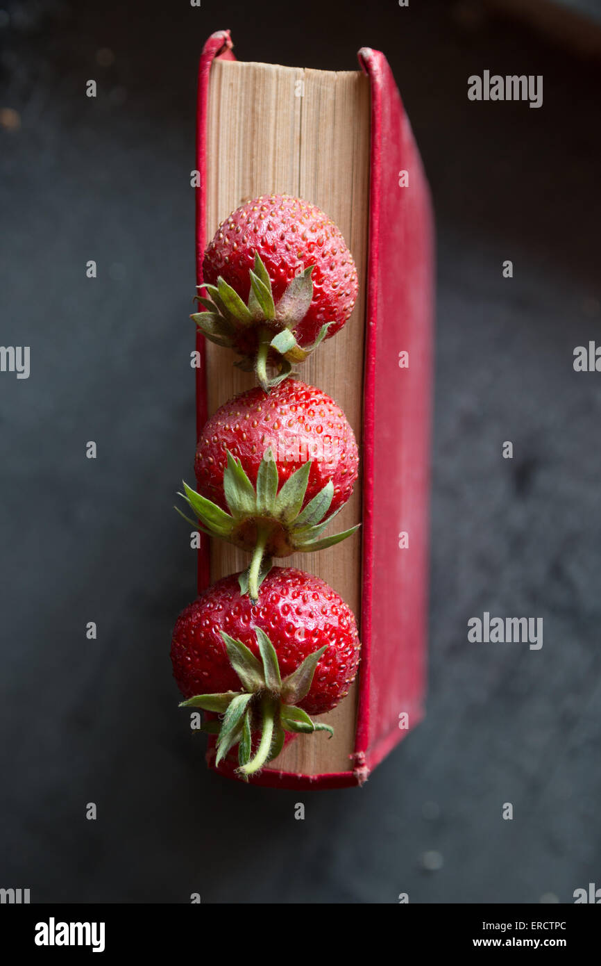 Erdbeeren und roten Kochbuch auf einem dunklen Tisch Stockfoto