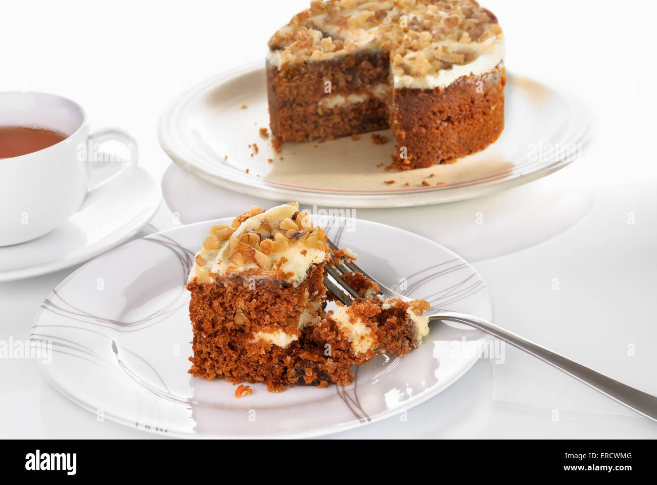 Karotte-Kuchen-Slice serviert auf einem Teller mit Gabel auf einer weißen Fläche. Tasse Tee. Selektiven Fokus Stockfoto