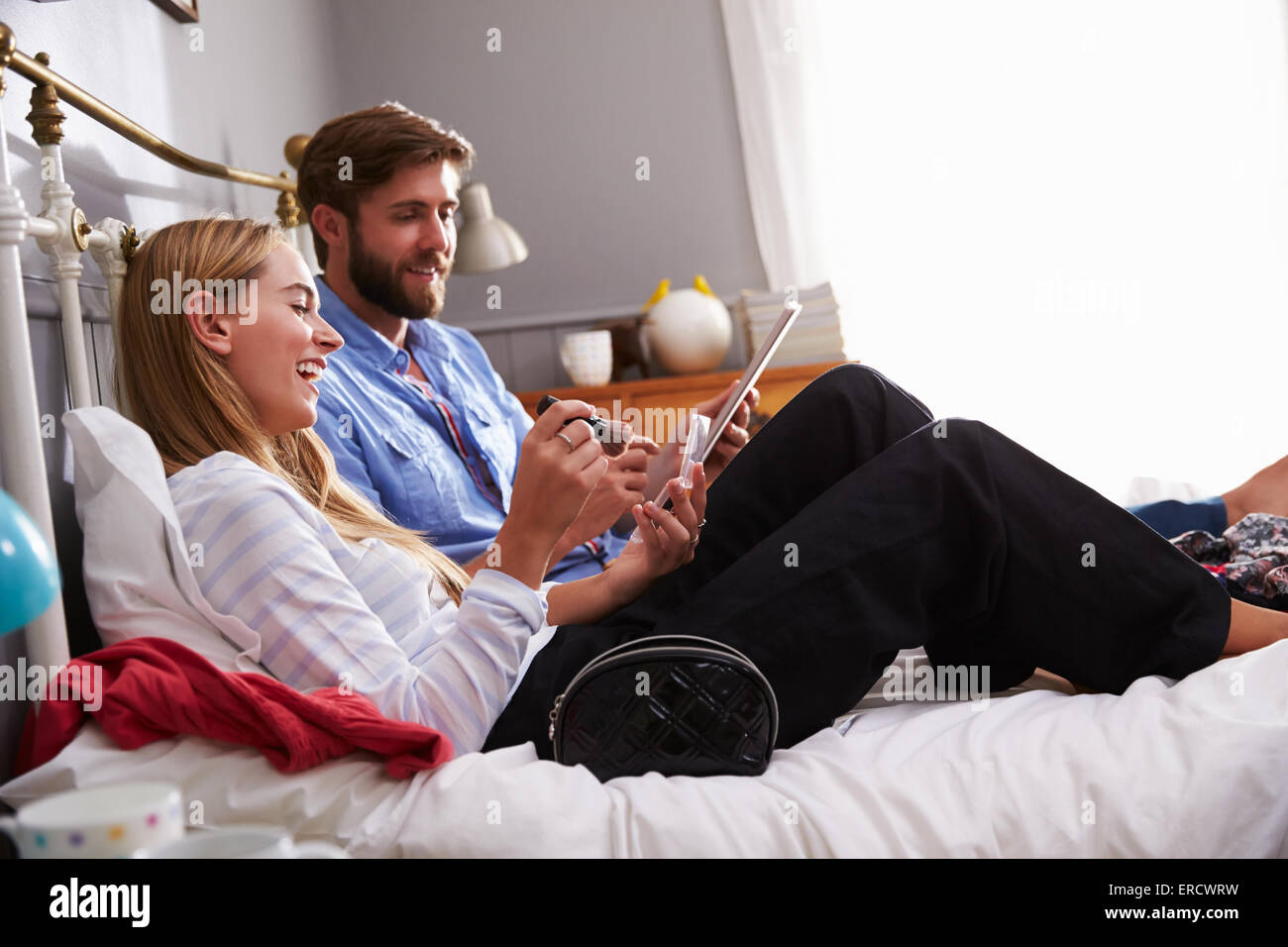 Frau legt auf Make Up als Mann nutzt digitale Tablet im Schlafzimmer Stockfoto