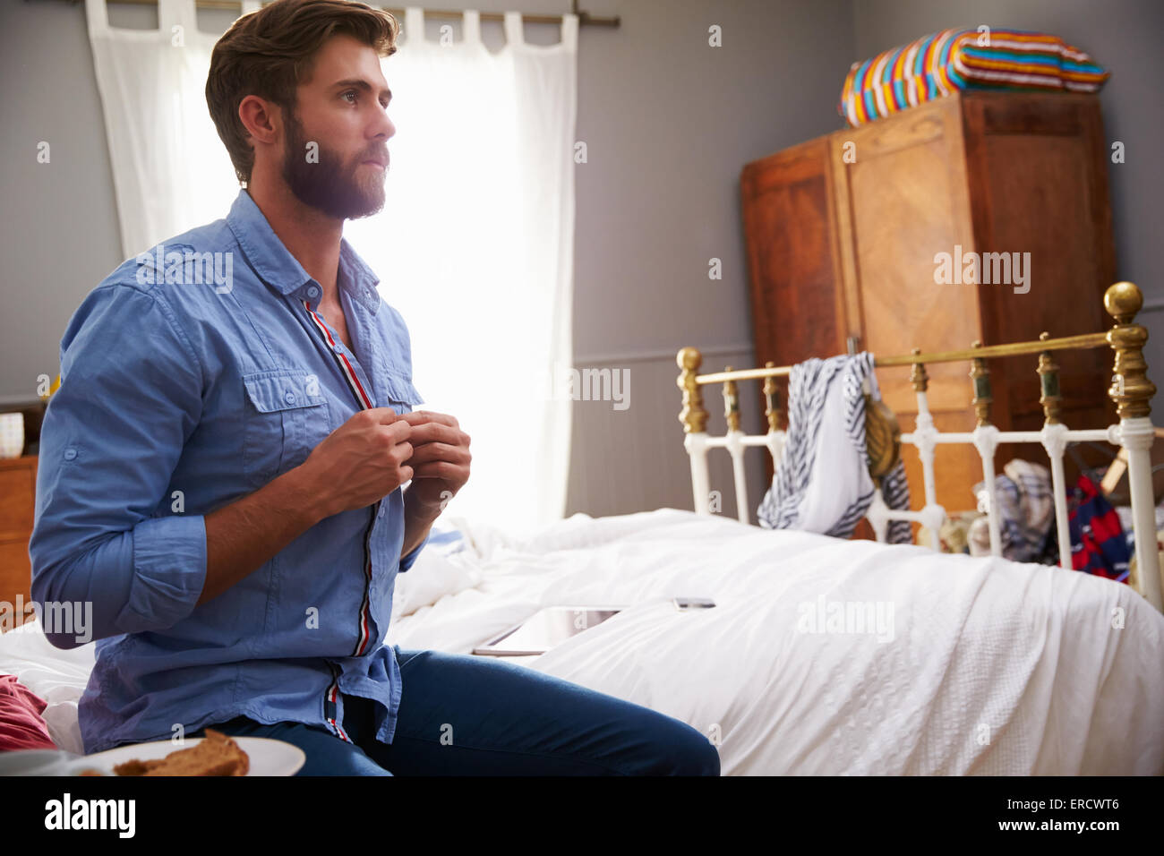 Mann sitzt auf dem Bett am Morgen anziehen Stockfoto