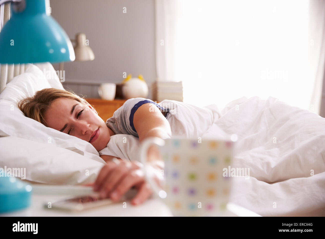 Schlafende Frau geweckt mit dem Handy im Schlafzimmer Stockfoto