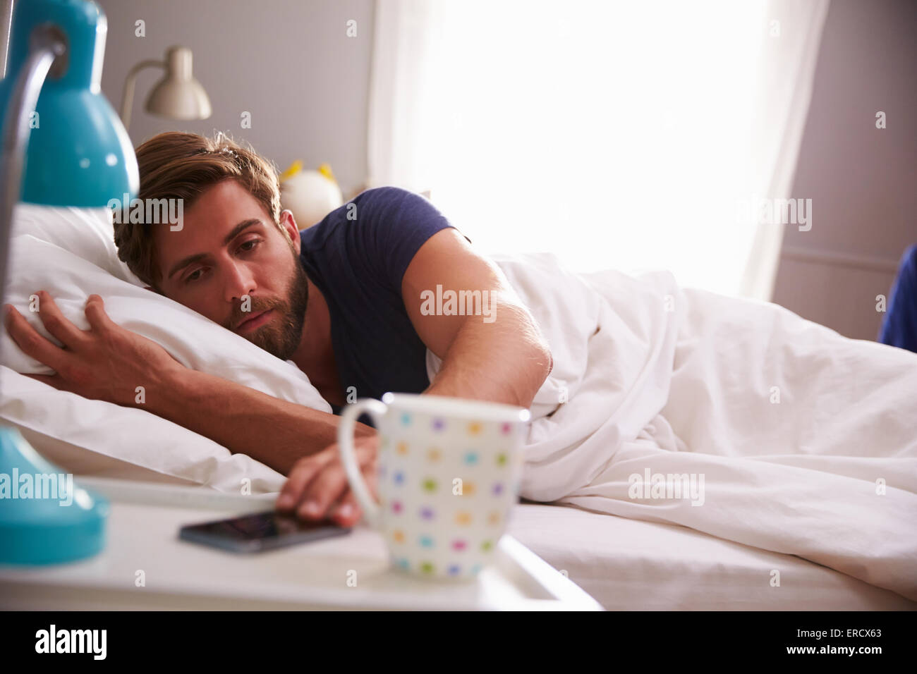 Schlafenden Mann geweckt mit dem Handy im Schlafzimmer Stockfoto