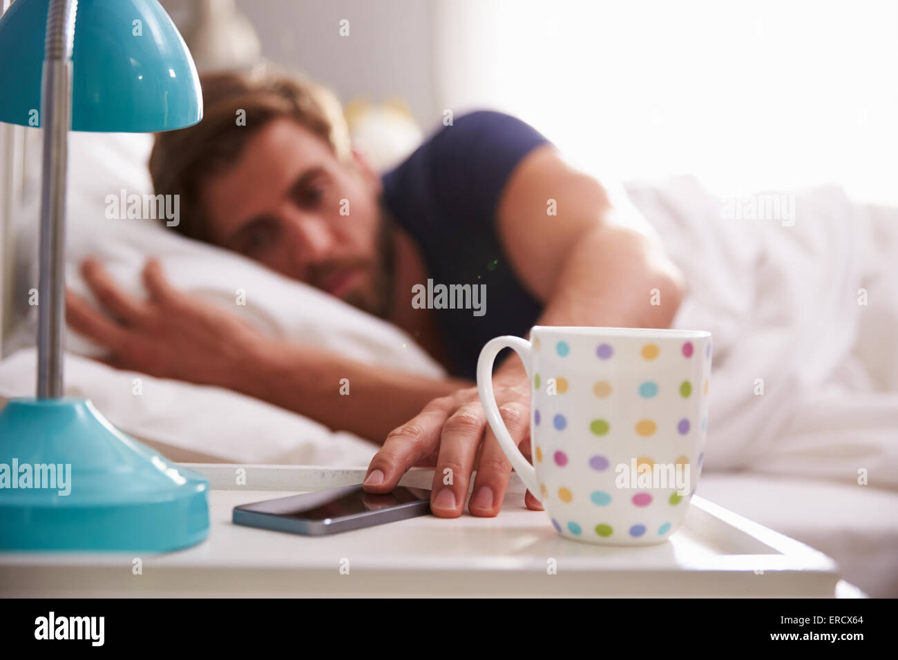 Schlafenden Mann geweckt mit dem Handy im Schlafzimmer Stockfoto
