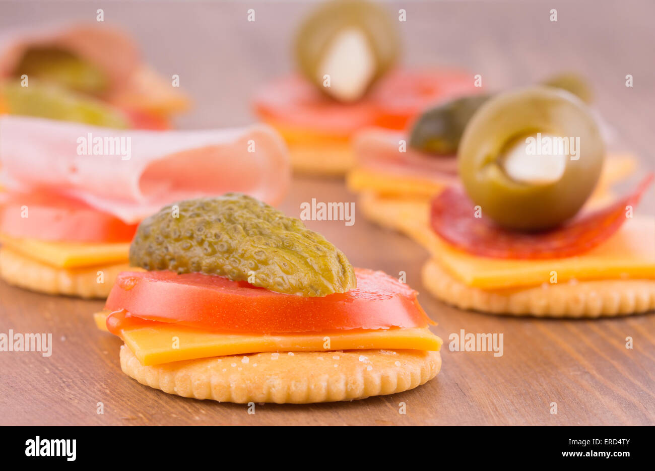 Cracker mit Käse, Tomaten und Gurke auf dunklen Holztisch Stockfoto