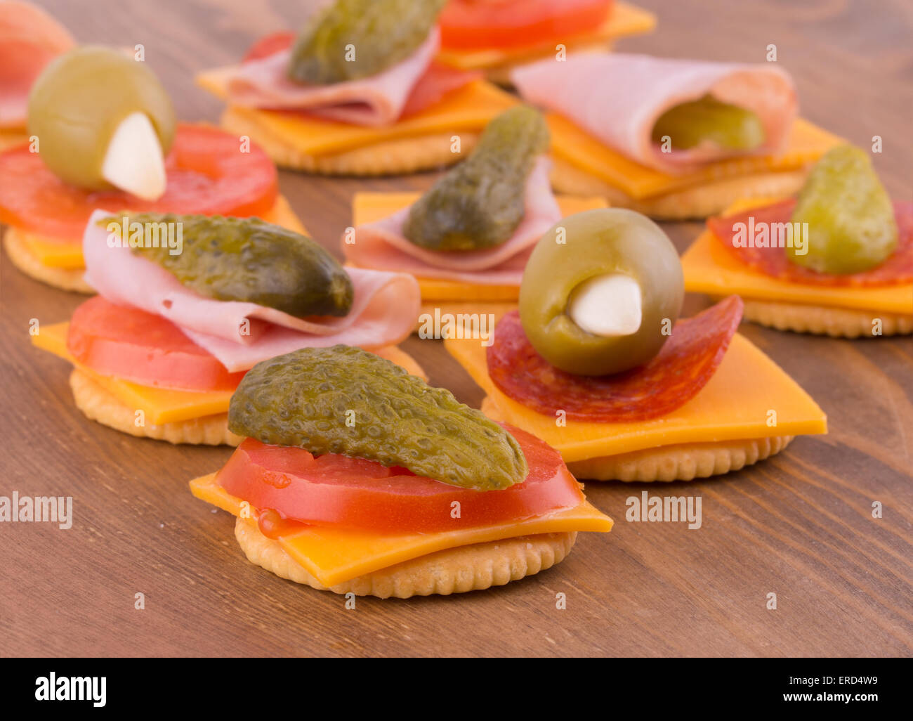 Cracker für Snacks, mit Käse, Tomate, Gurke, Peperoni, Oliven - auf dunklem Holz Tischplatte Stockfoto