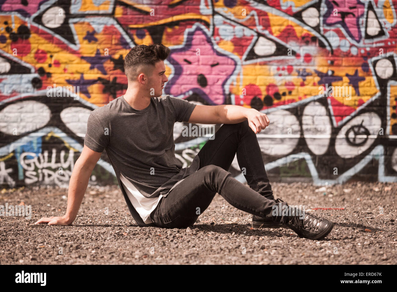 Ein junger Mann in seinen späten Teenager ist abgebildet in einem Grafitti hatte Umwelt in innere Stadt Birmingham UK Stockfoto