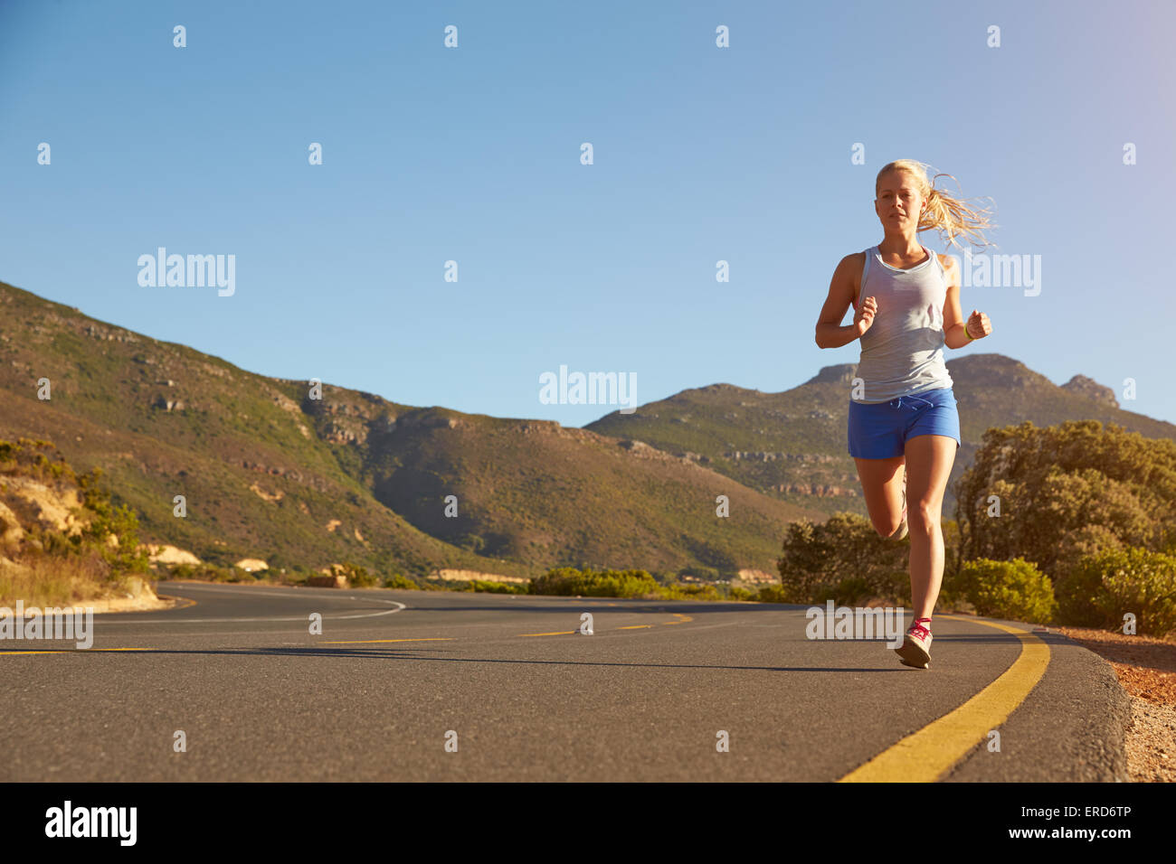 Young woman running on an empty road Stockfoto