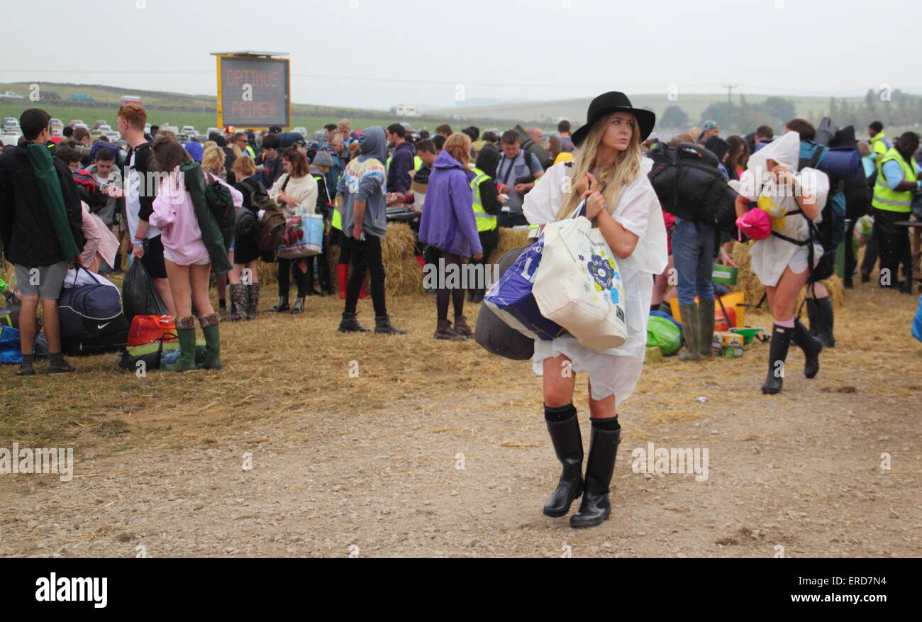 Eine Frau in Gummistiefeln, Hut und Kunststoff Poncho kommt in Regen zum Y nicht Festival, Peak District, Derbyshire Sommer 2014 Stockfoto