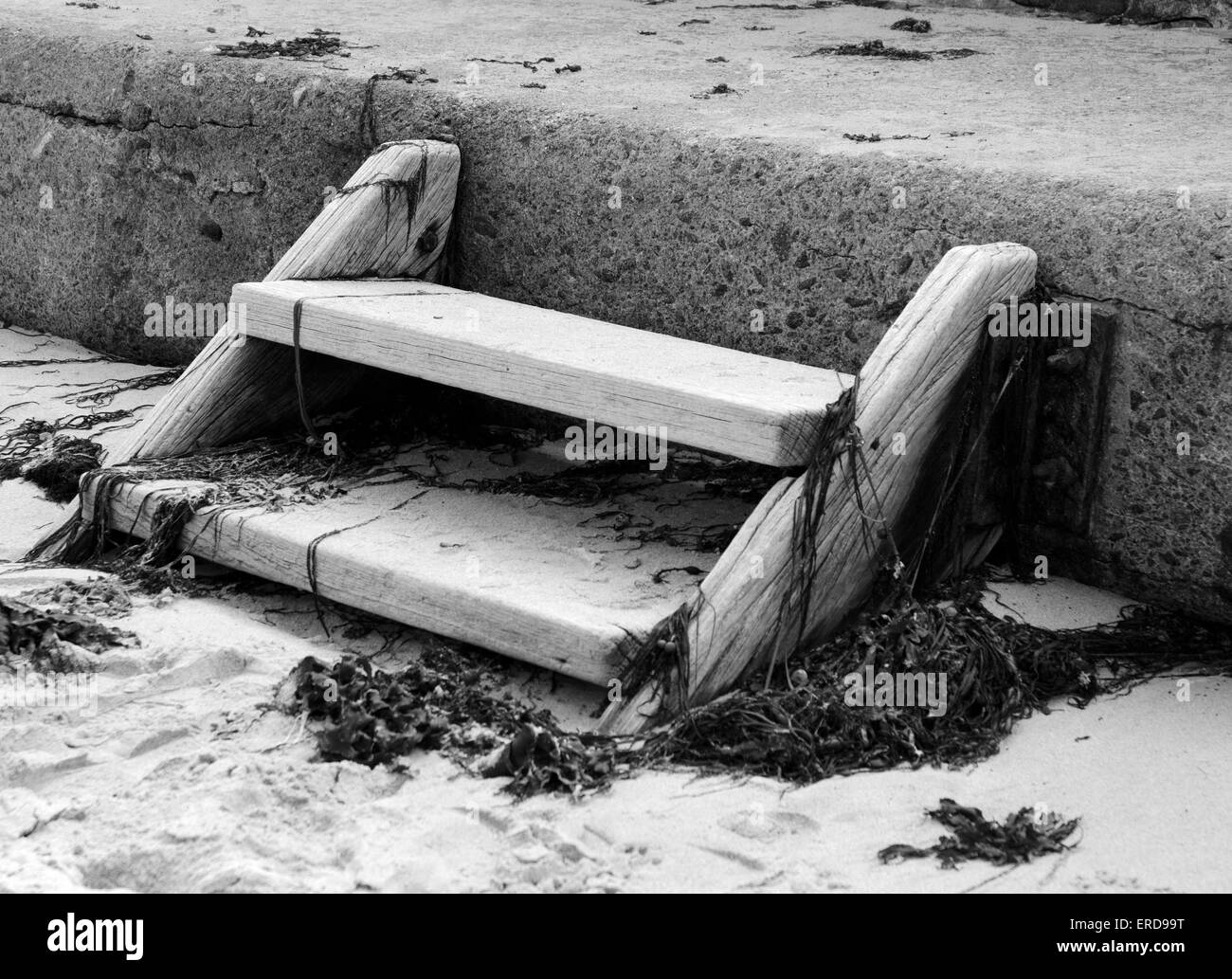 Holzstufen auf einem sandigen Strand mit Algen Stockfoto