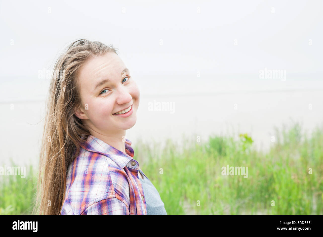 Reportageaufnahme lächelnden jungen blonden Frau am leeren Strand im karierten Hemd mit Textfreiraum Stockfoto