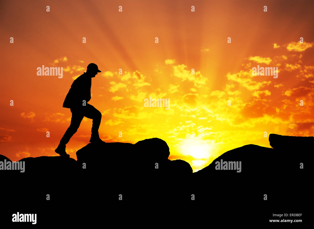 Silhouette eines Mannes auf einem Berg gegen Sonnenaufgang Klettern Stockfoto
